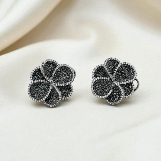 Pair of black and silver floral earrings on a white fabric background