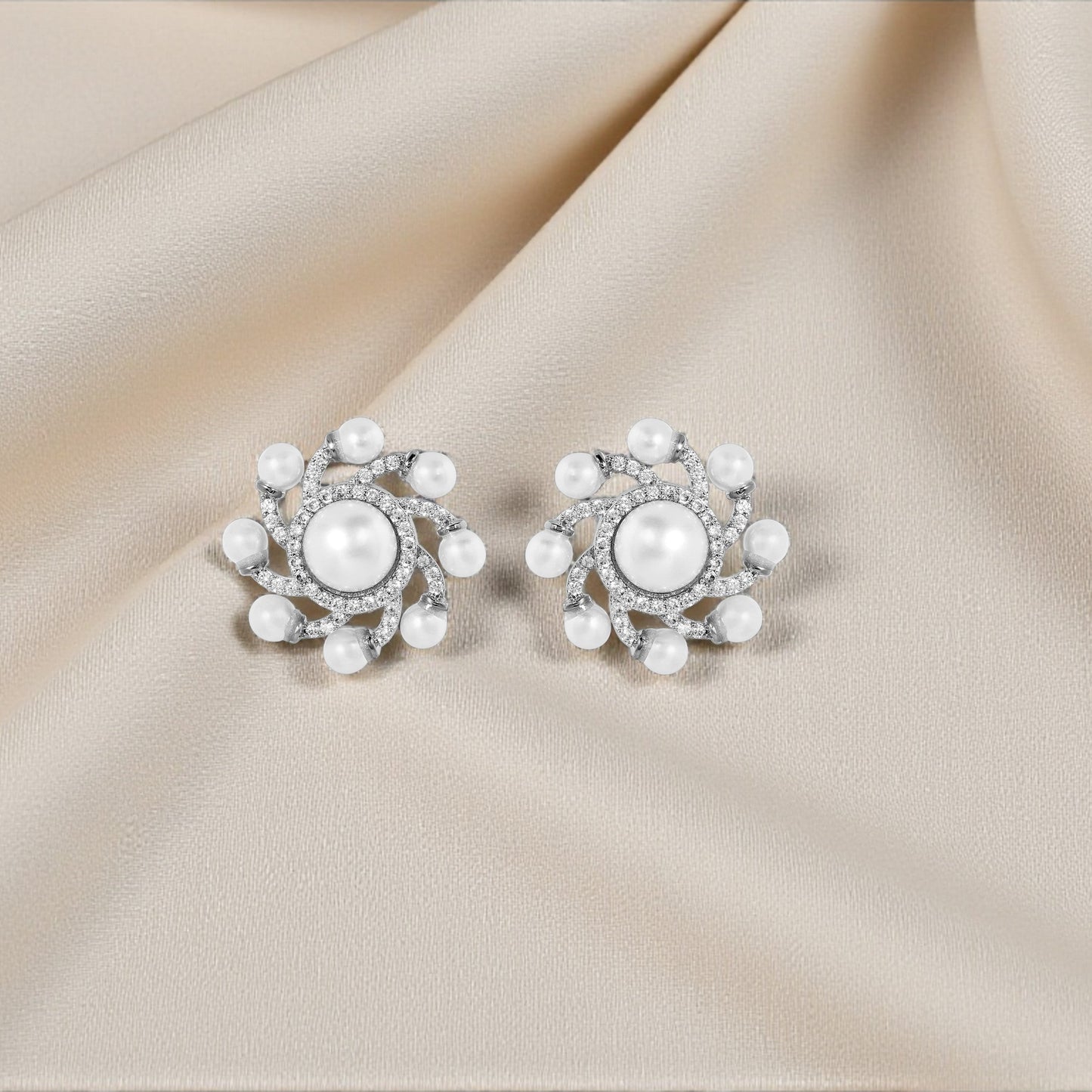 Pair of pearl earrings on a beige fabric background