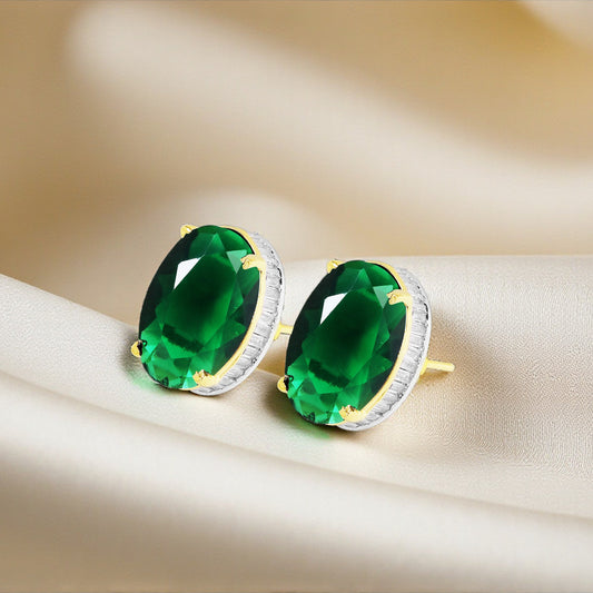 Pair of green gemstone earrings on a beige fabric background