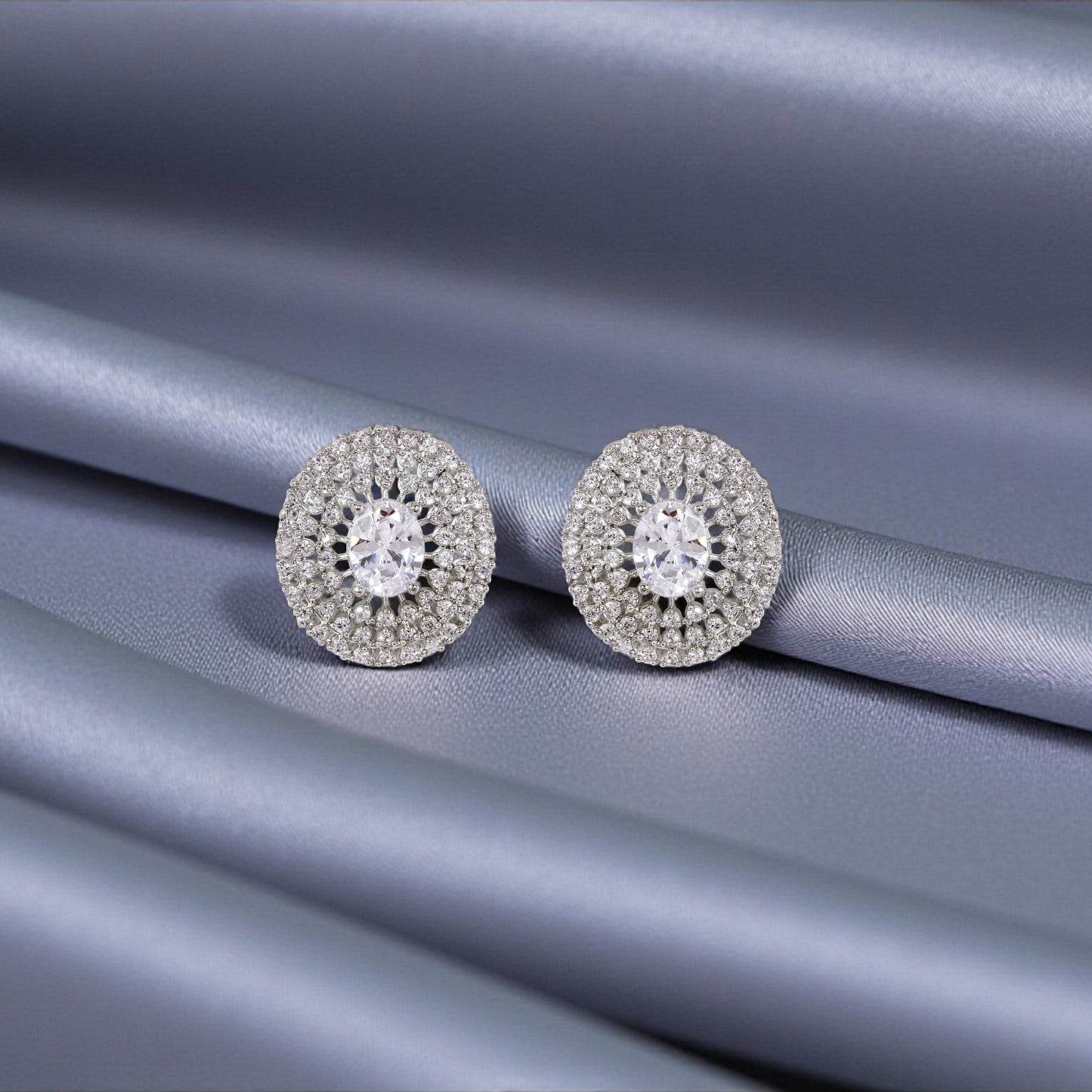 Pair of silver earrings with gemstones on a gray fabric background