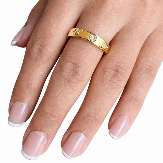 Gold ring with small diamonds on a hand against a white background