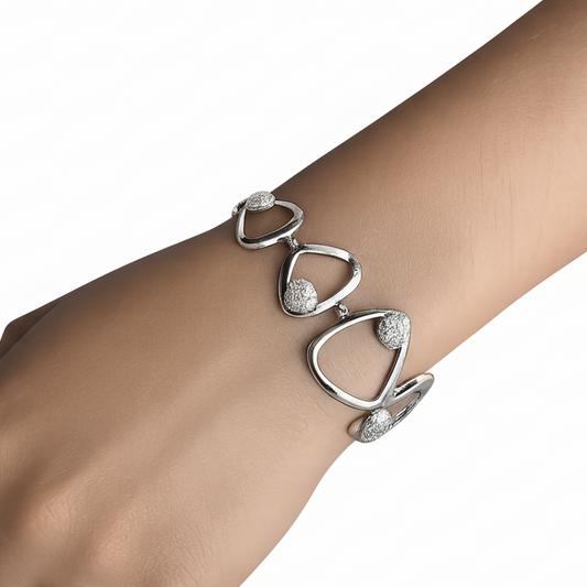 Silver bracelet with heart-shaped links on a wrist against a white background