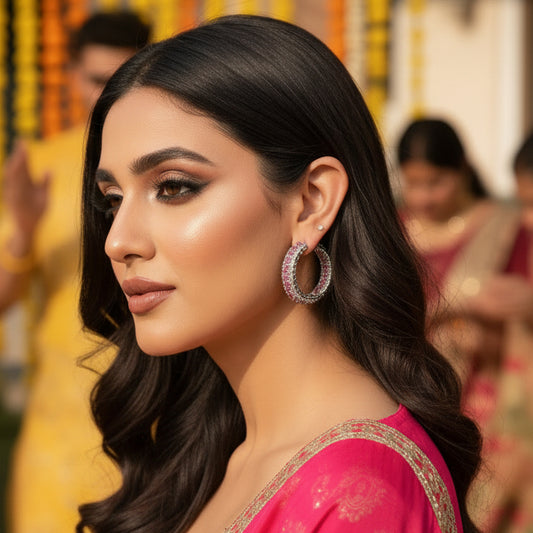 Close-up of a person wearing a silver hoop earring with pink gemstones.