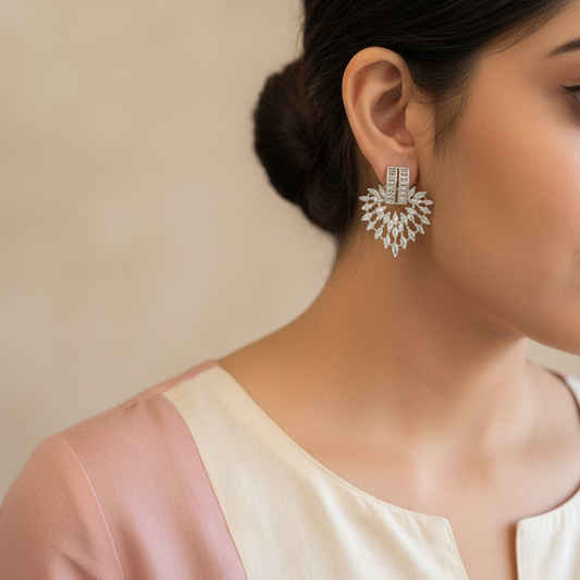 Woman wearing a pair of large, ornate earrings with a neutral background