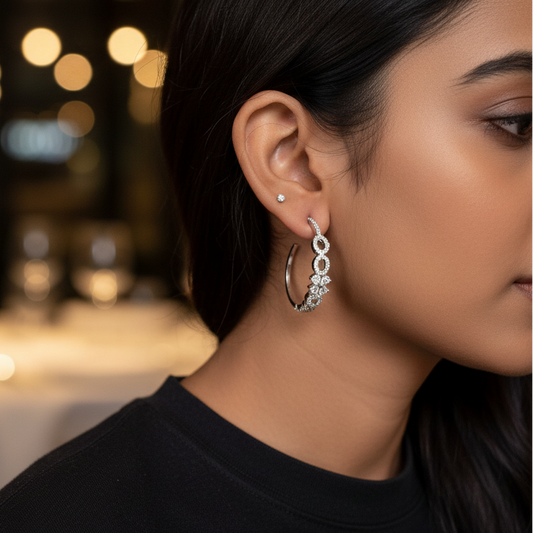 Close-up of a woman wearing silver hoop earrings with blurred lights in the background