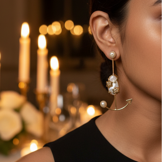Woman wearing pearl earrings in a dimly lit room with candles and flowers.