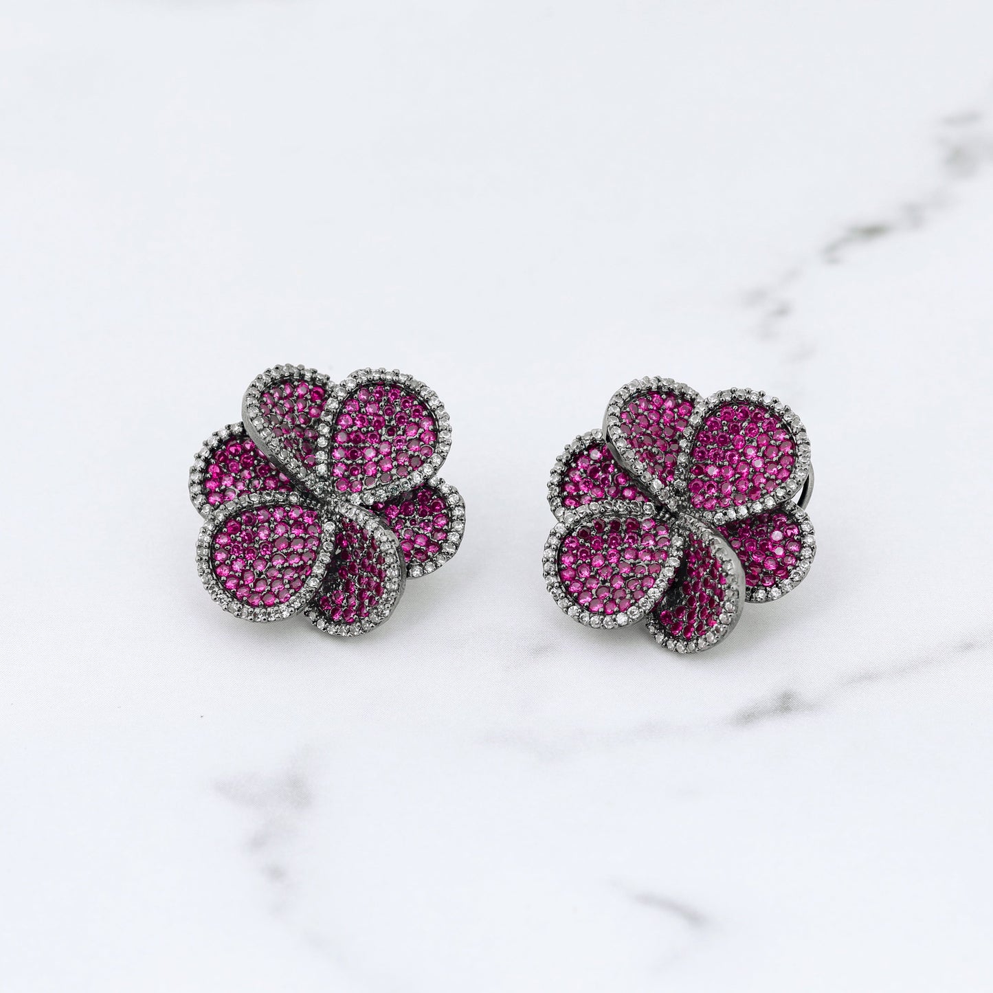 Pair of pink flower-shaped diamond earrings on a marble surface