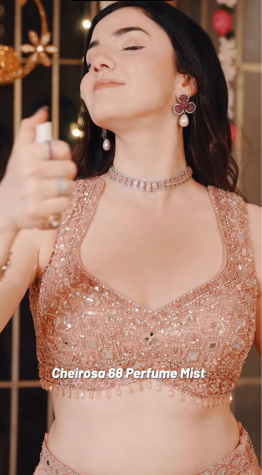 Woman holding a spray bottle labeled 'Cheirosa 68 Perfume Mist' with a blurred background