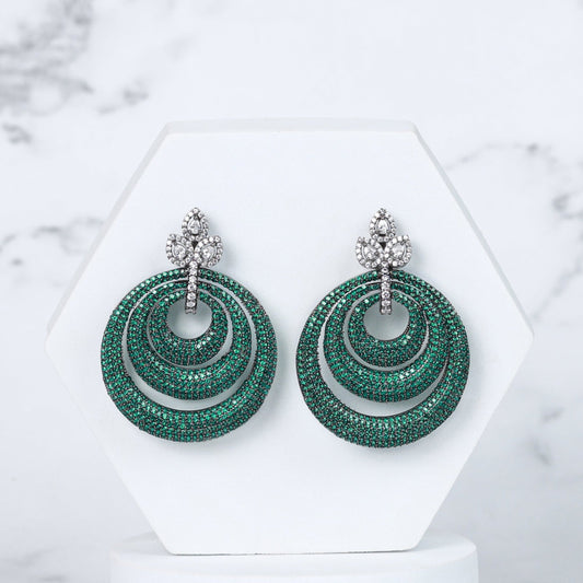 Green diamond earrings on a white stand with a marble background