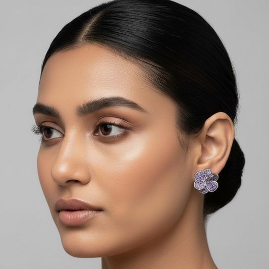 Close-up of a woman wearing purple floral earrings against a gray background