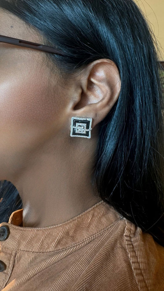 Person wearing a square earring with a logo, close-up of the ear.