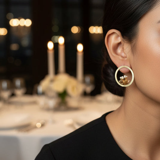 Woman wearing gold hoop earrings with a blurred background of a dining table.