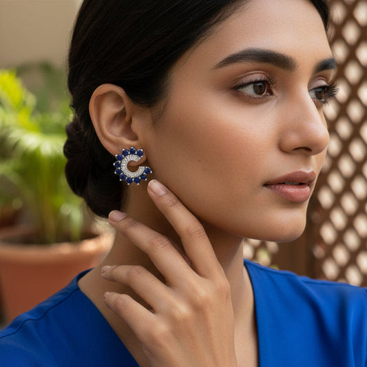 Woman wearing blue earrings with a blurred outdoor background