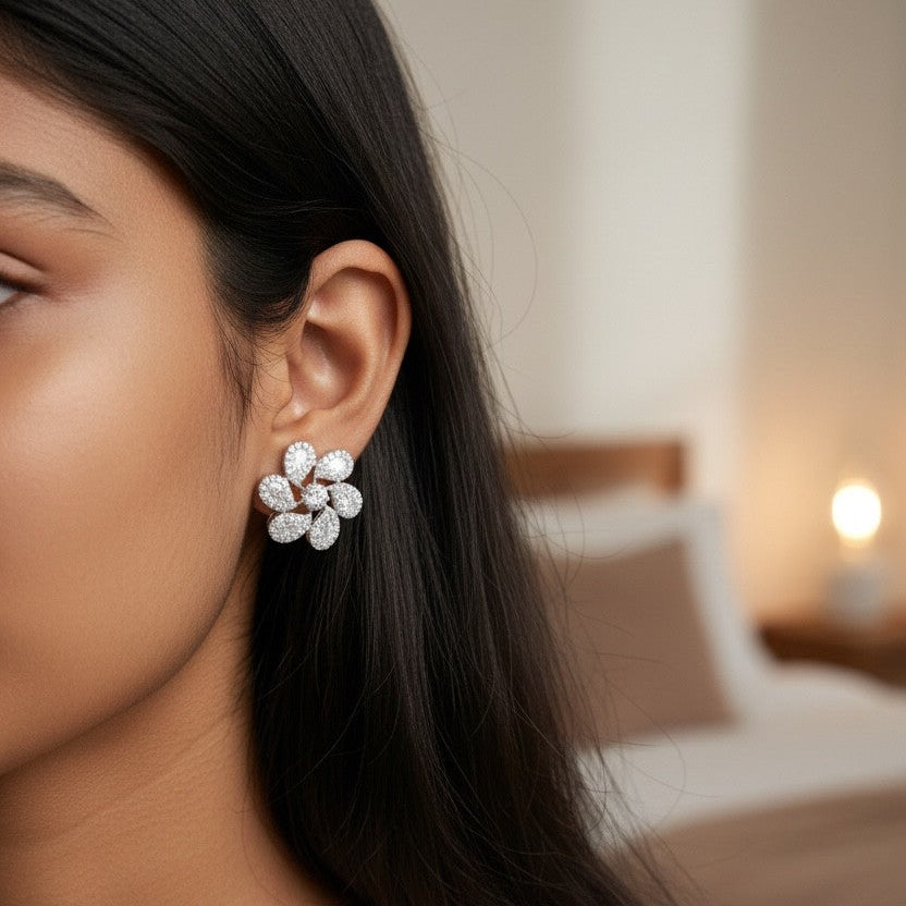 Close-up of a woman wearing floral earrings with a blurred bedroom background