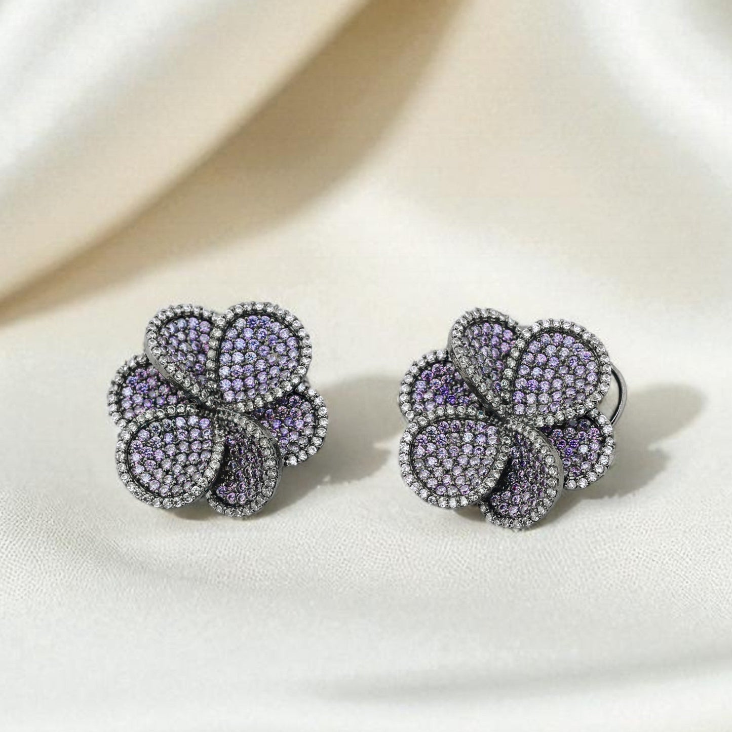 Pair of floral earrings with purple stones on a white surface