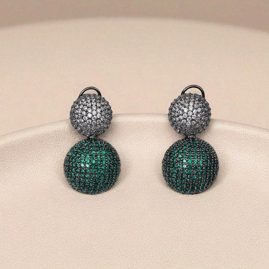Pair of earrings with green and silver design on a beige background