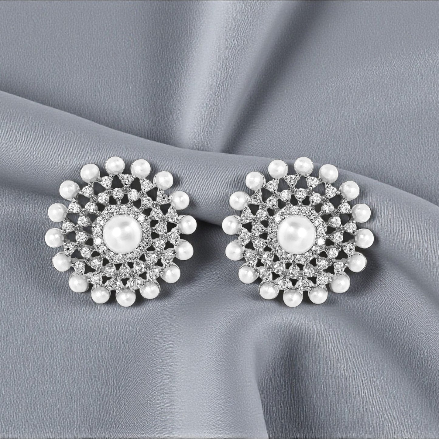 Pair of silver floral earrings with pearls on a gray fabric background