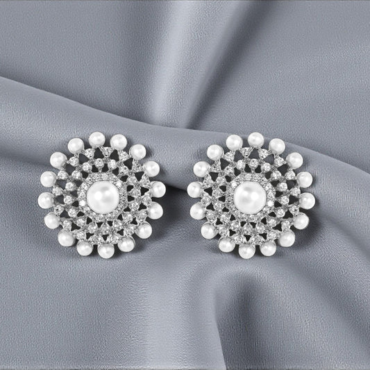 Pair of silver floral earrings with pearls on a gray fabric background