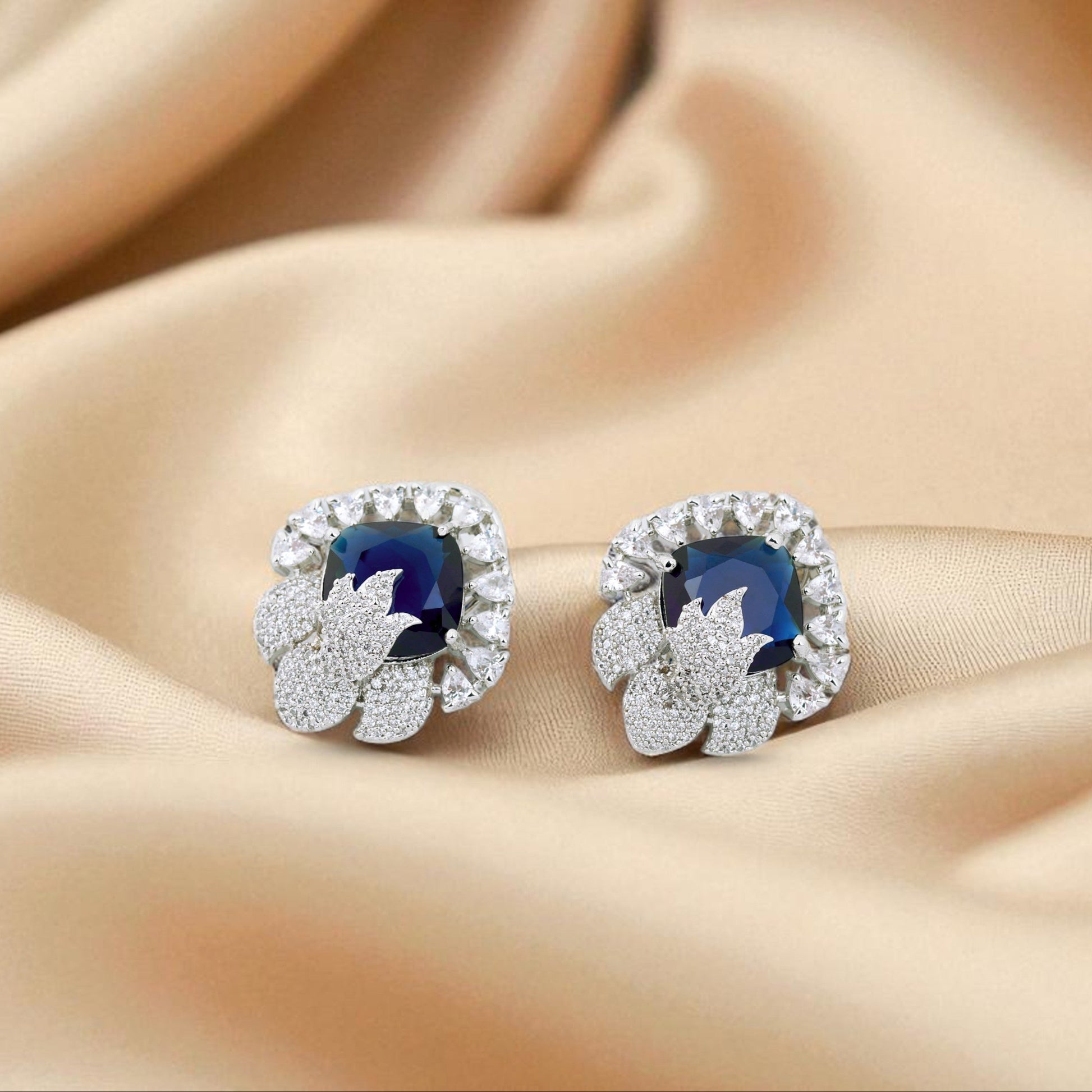 Pair of silver earrings with blue gemstones on a beige fabric background