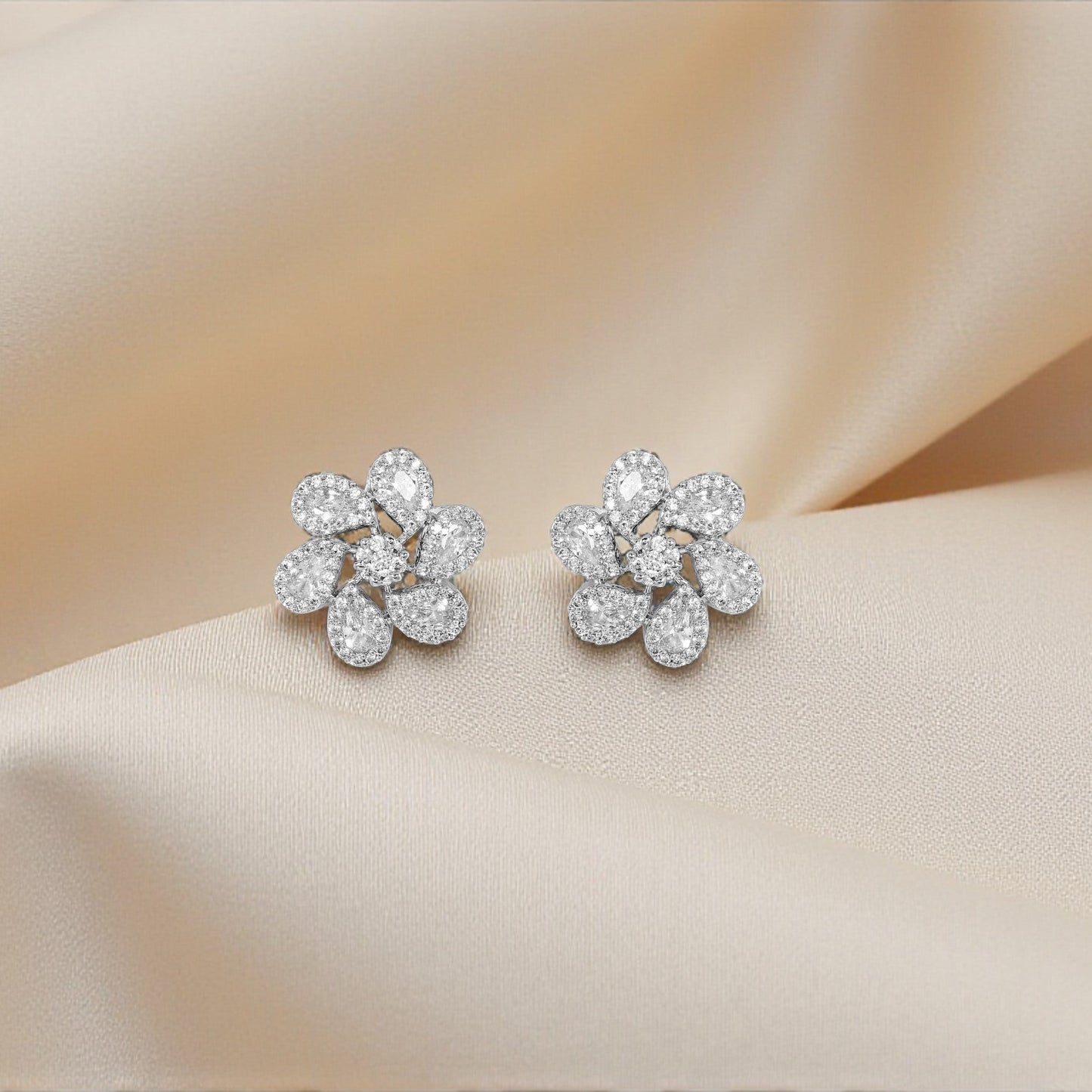Pair of diamond earrings on a soft beige fabric background