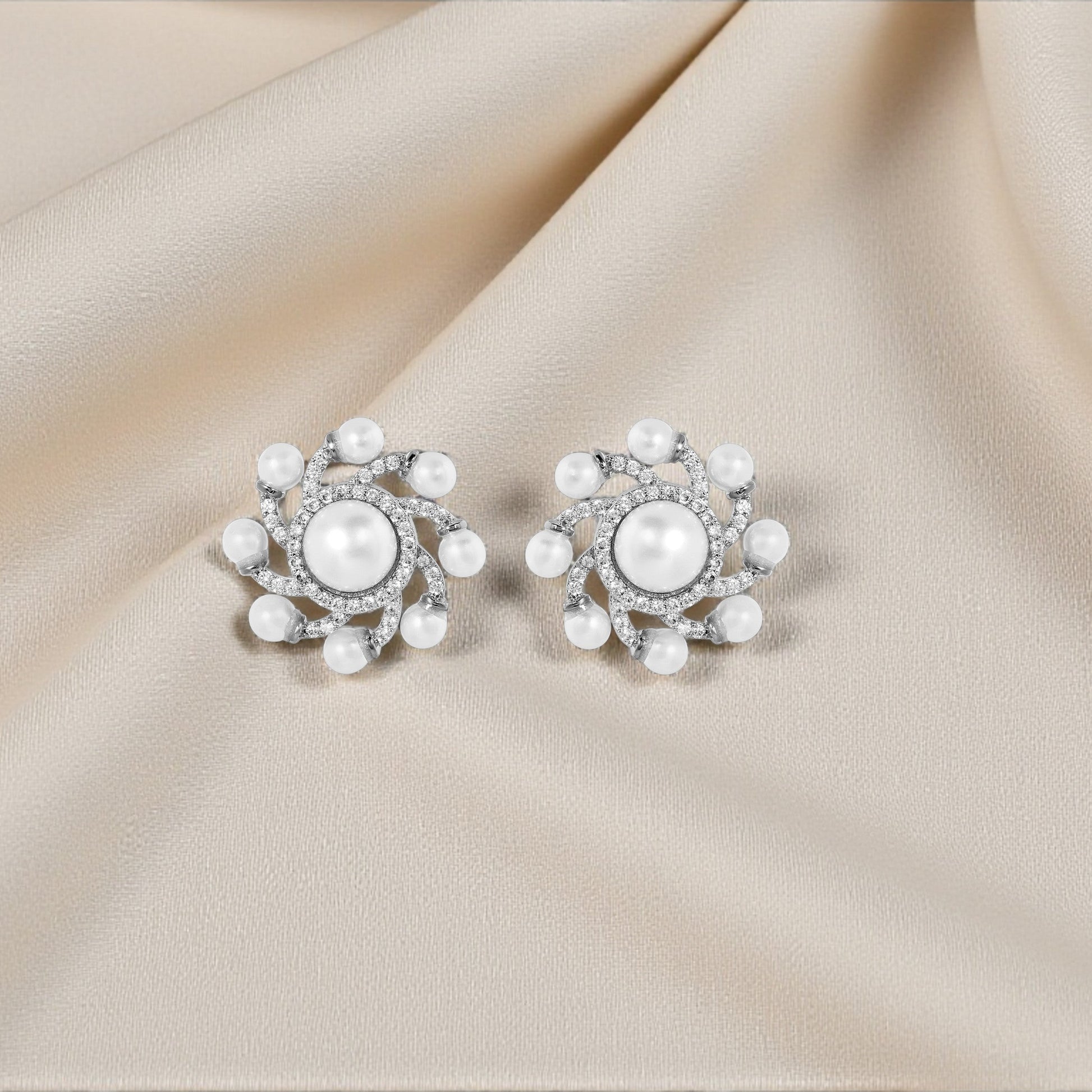 Pair of pearl earrings on a beige fabric background