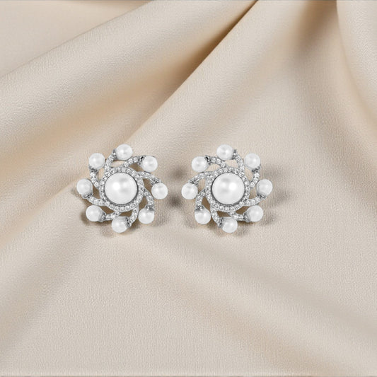 Pair of pearl earrings on a beige fabric background