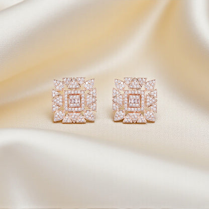 Pair of square-shaped earrings with pink gemstones on a satin surface