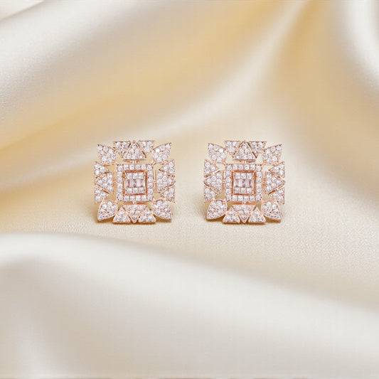 Pair of square-shaped earrings with pink gemstones on a satin surface
