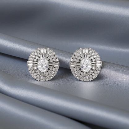 Pair of silver earrings with clear gemstones on a gray fabric background
