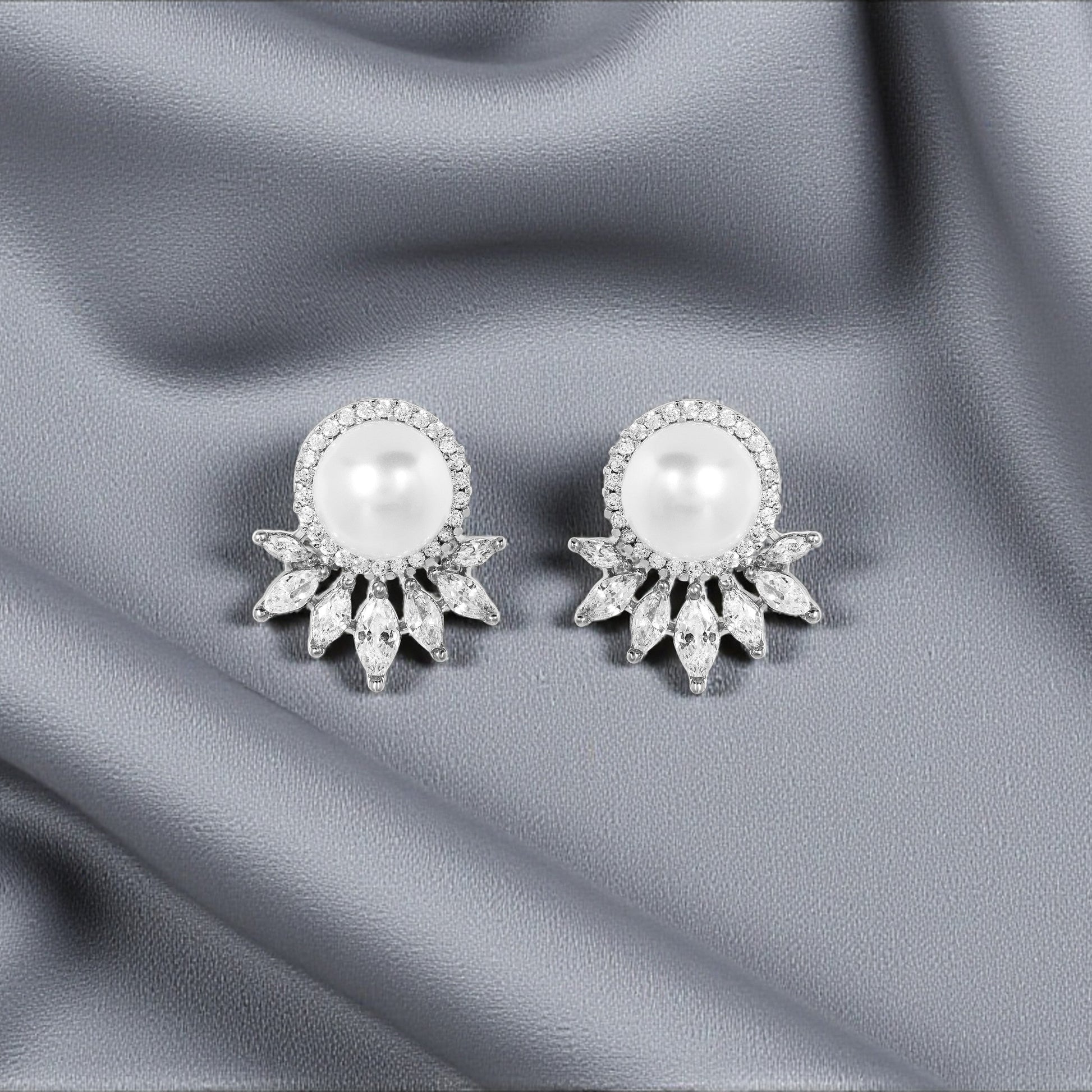 Pair of pearl earrings on a gray fabric background