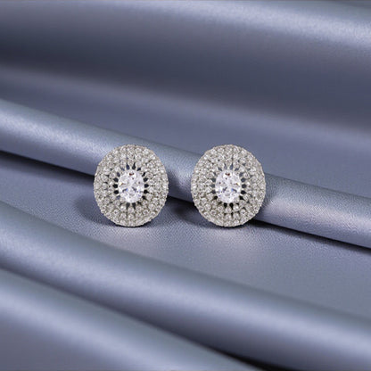 Pair of silver earrings with gemstones on a gray fabric background