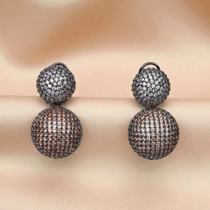 Pair of double-ball earrings with intricate detailing on a soft beige background