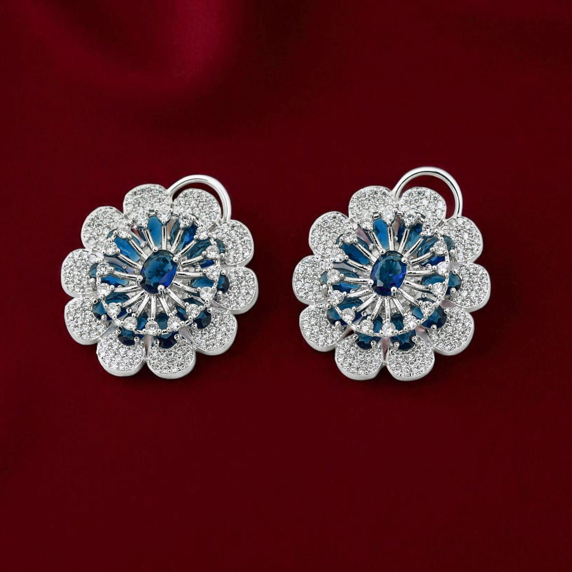 Pair of floral earrings with blue gemstones on a red background