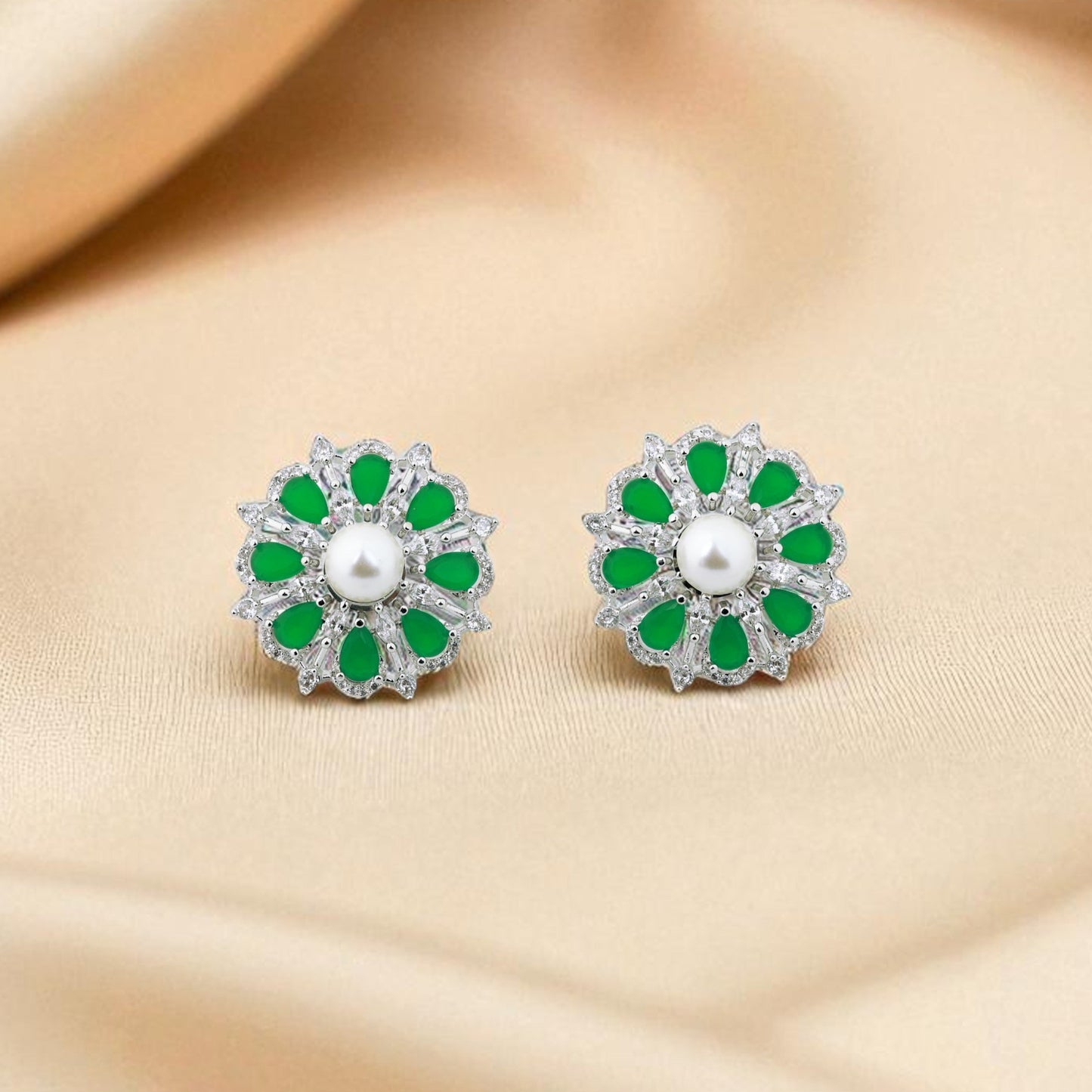 Pair of earrings with green and white stones on a beige fabric background