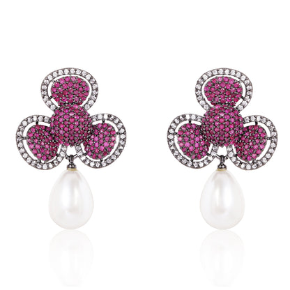 Pair of earrings with pink gemstones and pearl drops on a white background