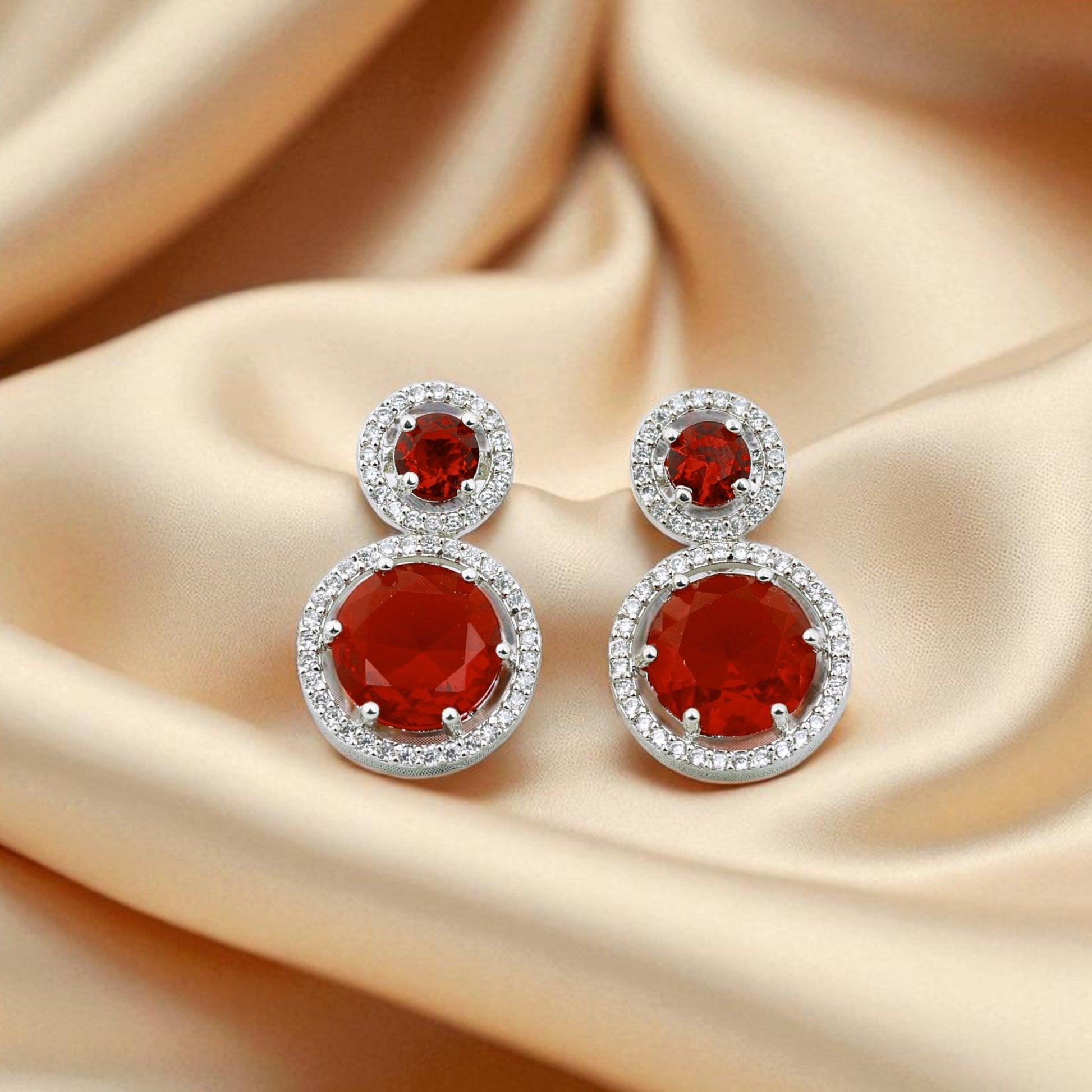 Pair of red gemstone earrings on beige fabric