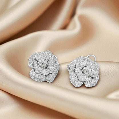Silver rose-shaped earrings on beige satin fabric