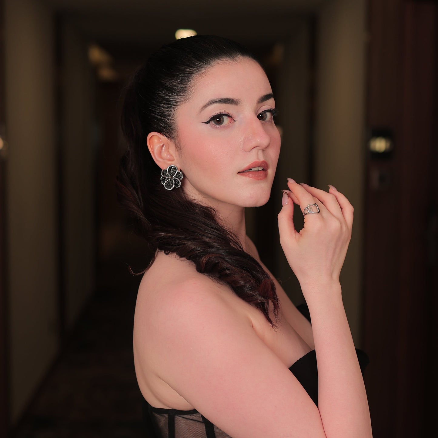 Woman in a black dress with sheer panels posing indoors.