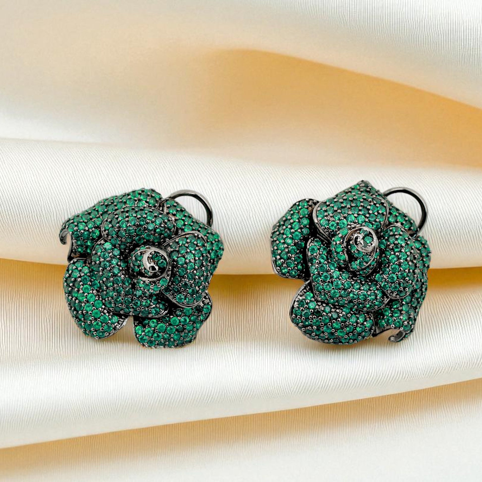 Green floral earrings on a textured fabric background