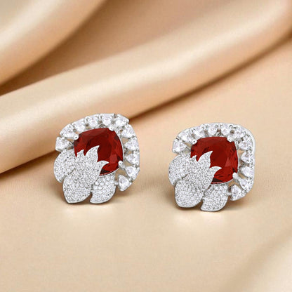 Pair of earrings with red gemstones and diamond-like stones on a beige fabric background