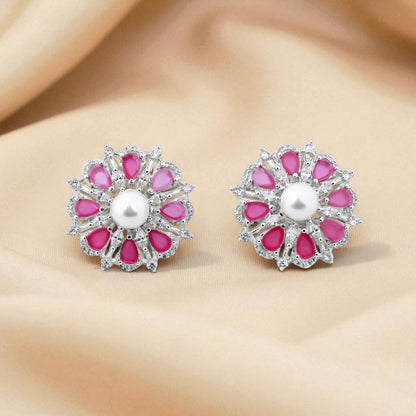 Pair of pink floral earrings with a pearl center on a beige fabric background