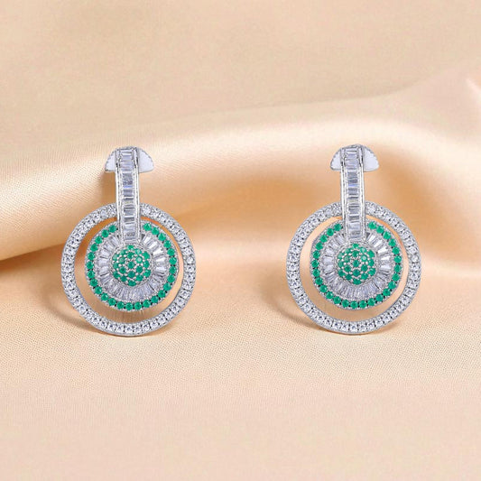 Pair of earrings with green gemstones on a beige fabric background