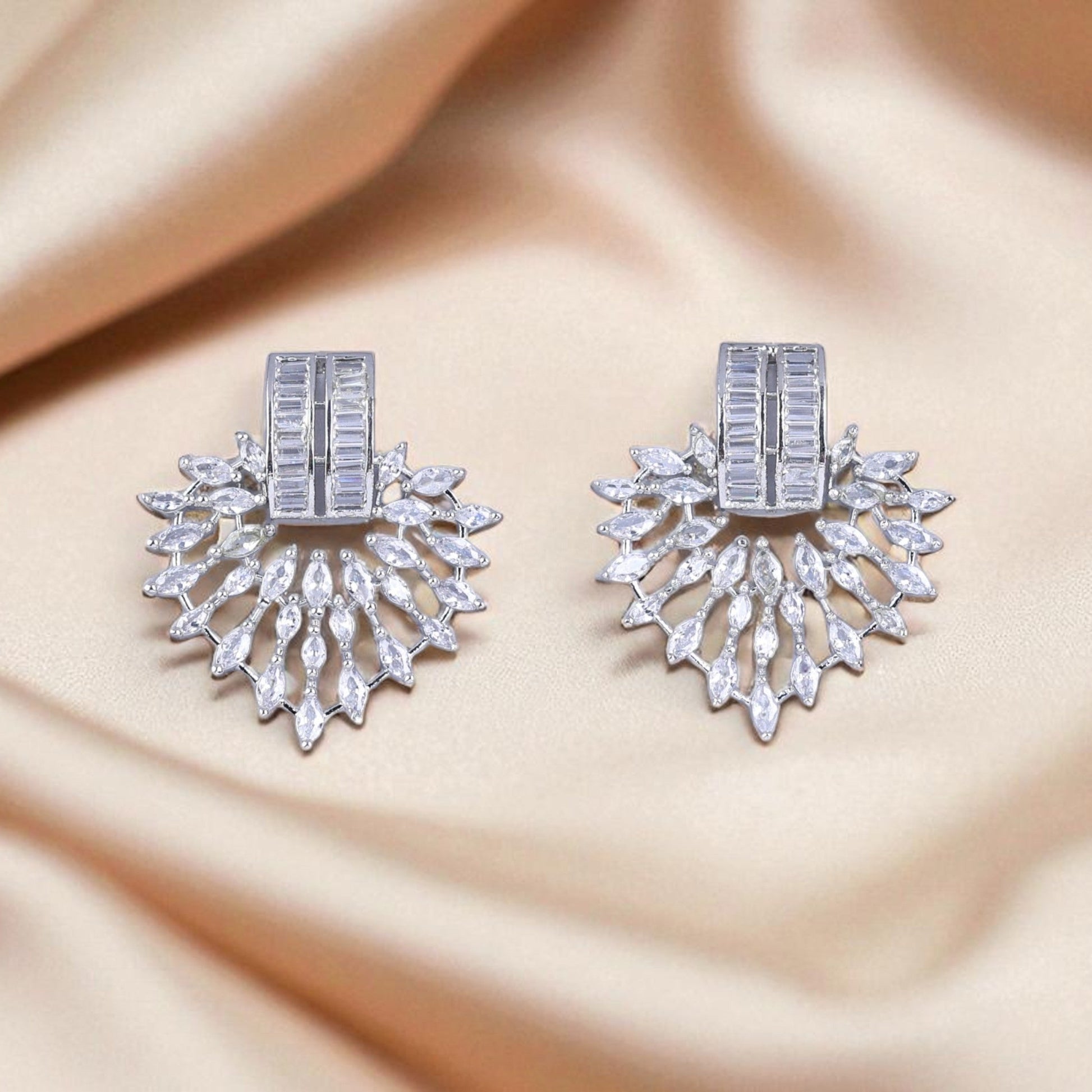 Pair of silver earrings with gemstones on a beige fabric background