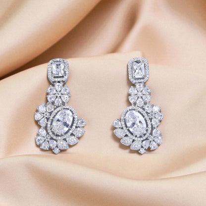 Pair of diamond earrings on a beige fabric background
