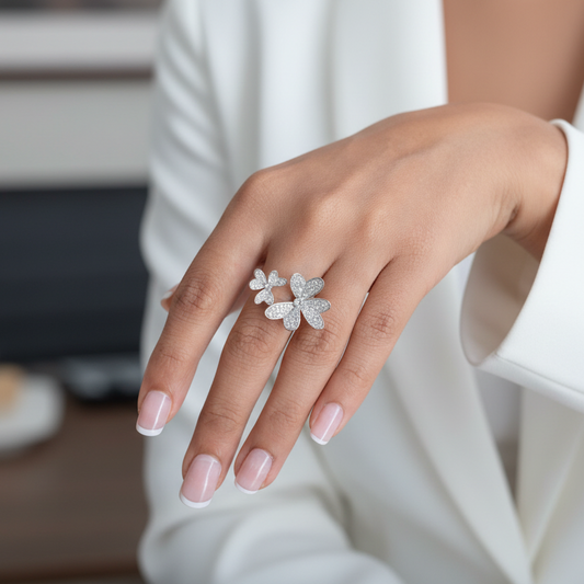 Hand wearing a silver ring with floral design, blurred indoor setting
