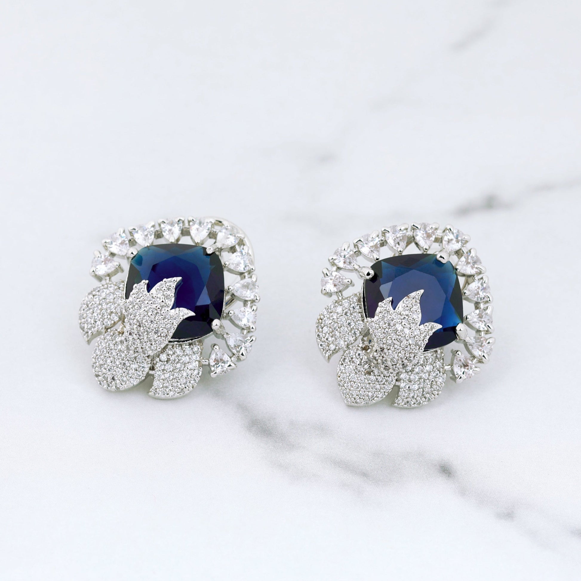 Pair of earrings with blue gemstones on a marble surface