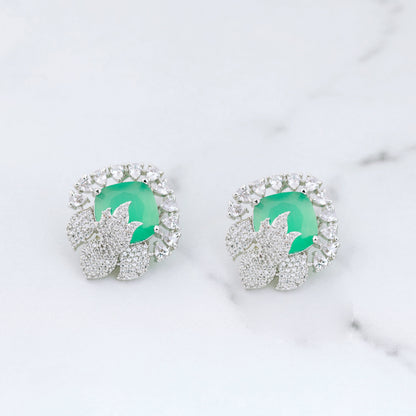 Pair of earrings with green gemstones on a marble surface