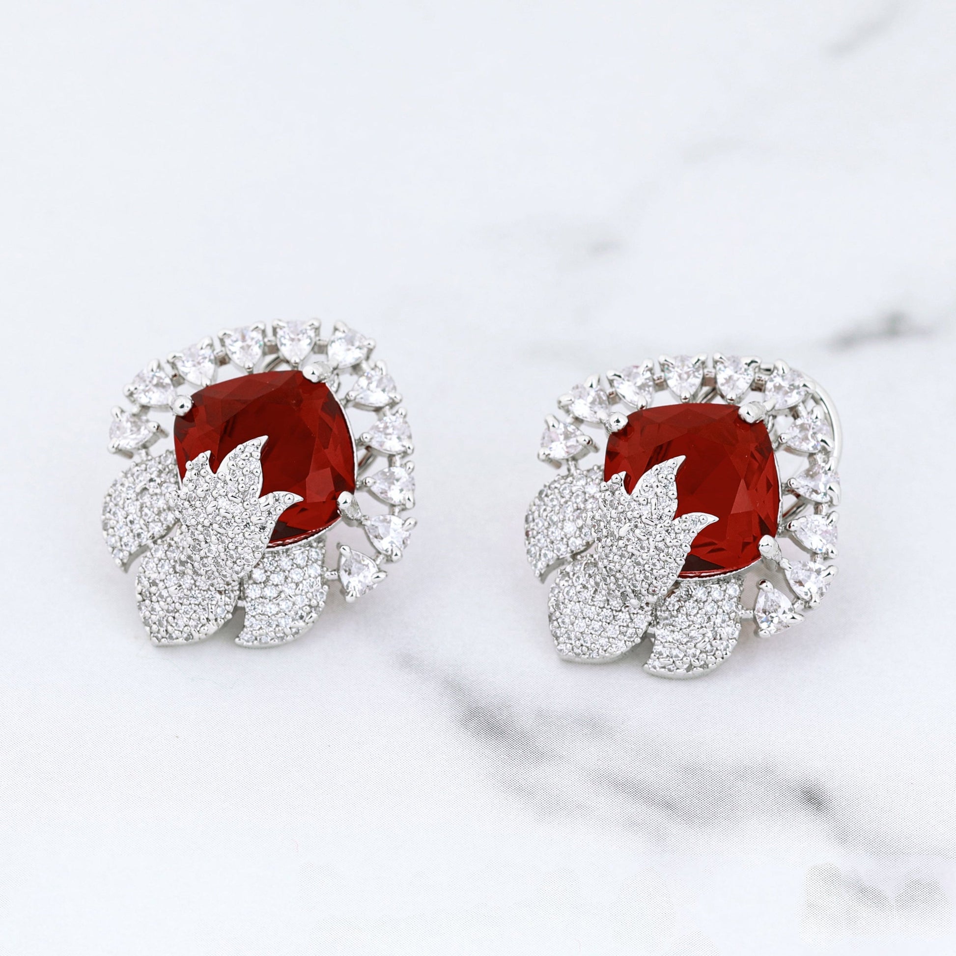 Pair of earrings with red gemstones on a marble surface