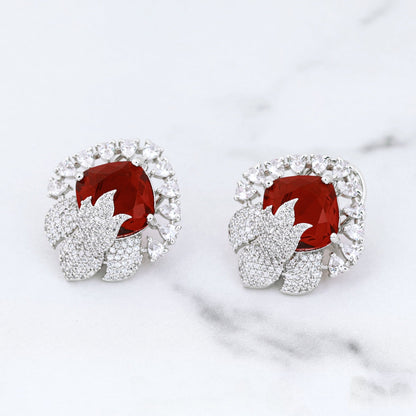 Pair of earrings with red gemstones on a marble surface