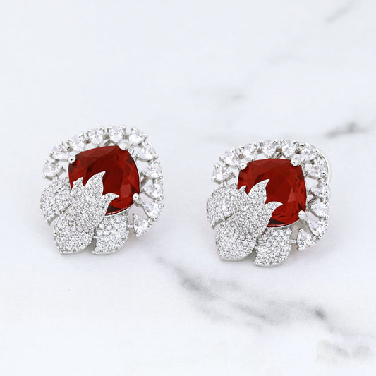 Pair of earrings with red gemstones on a marble surface
